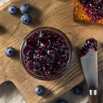 Blueberry jam in a jar as seen from overhead with spreader and toast.