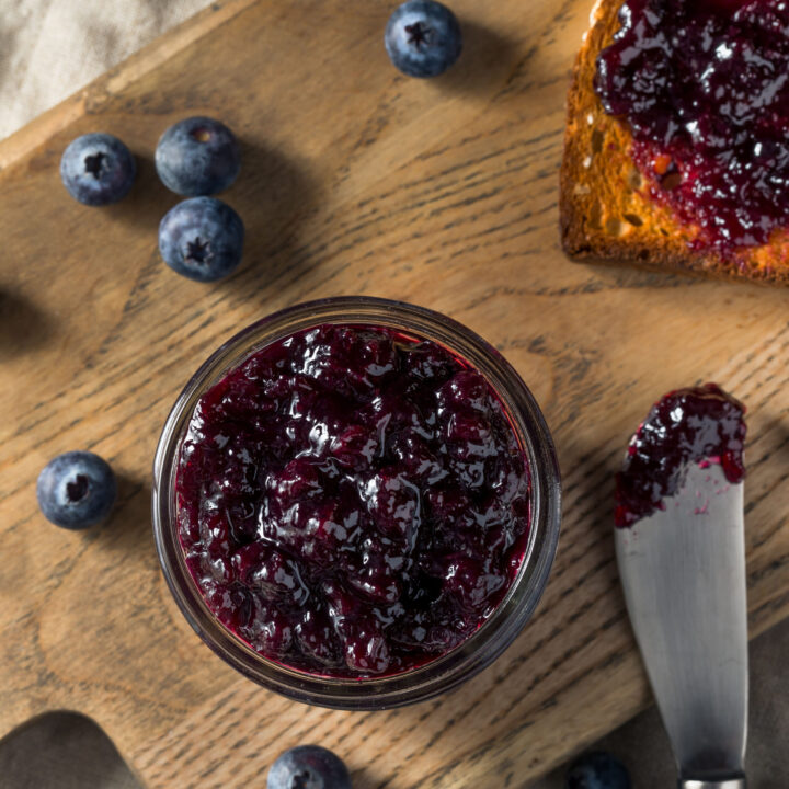 Blueberry jam in a jar as seen from overhead with spreader and toast.