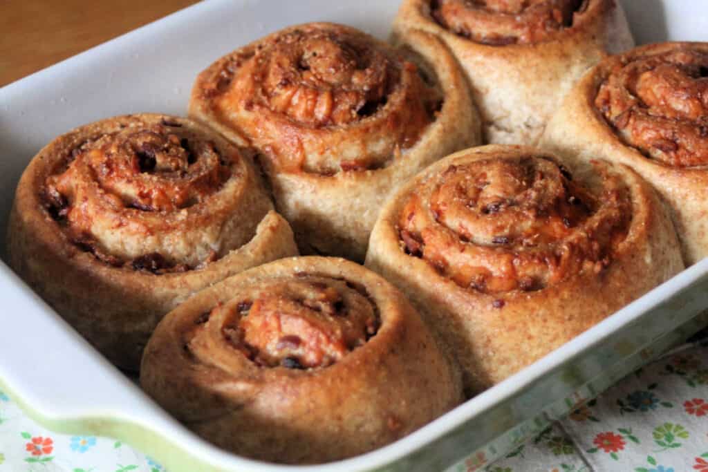 6 bacon cheddar rolls in a green and white casserole dish.