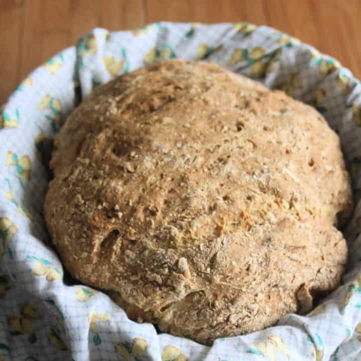 A round loaf of Irish Soda Bread sitting inside a linen lined basket.