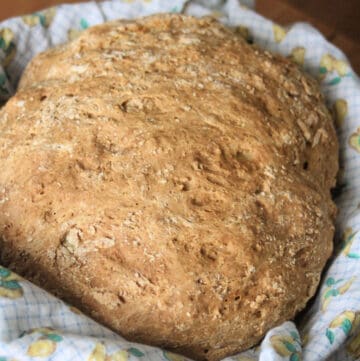 A round loaf of Irish Soda Bread sitting inside a linen lined basket.