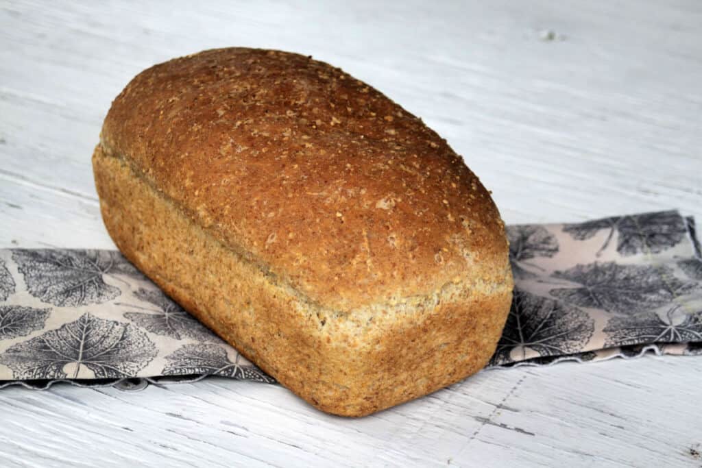 A loaf of mulitgrain bread sitting on napkin on a white table.