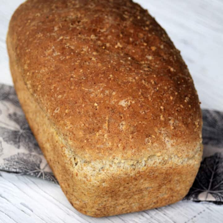 A loaf of mulitgrain bread sitting on napkin on a white table.