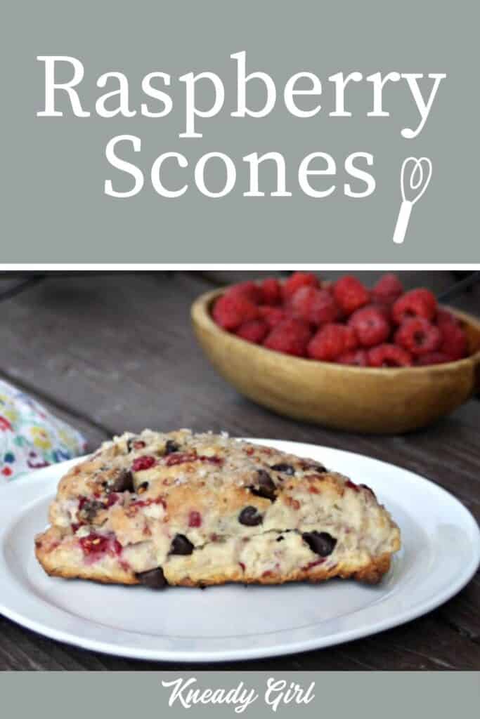 A raspberry chocolate chip scone on a white plate sitting in front of a bowl of berries with text overlay. 