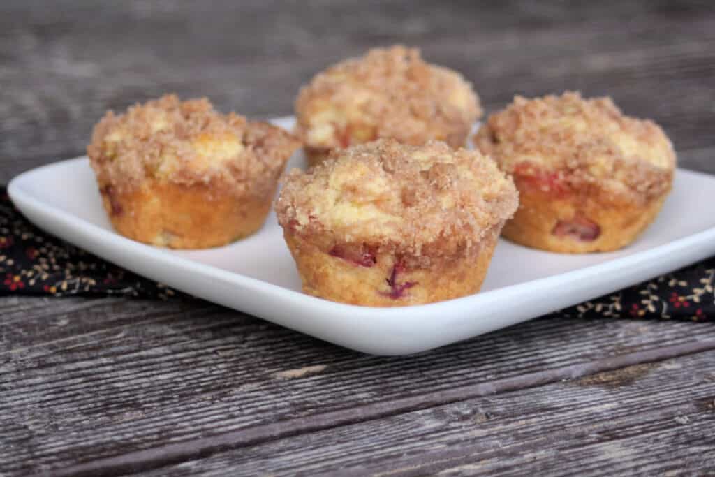 4 rhubarb muffins sitting on a square white plate.