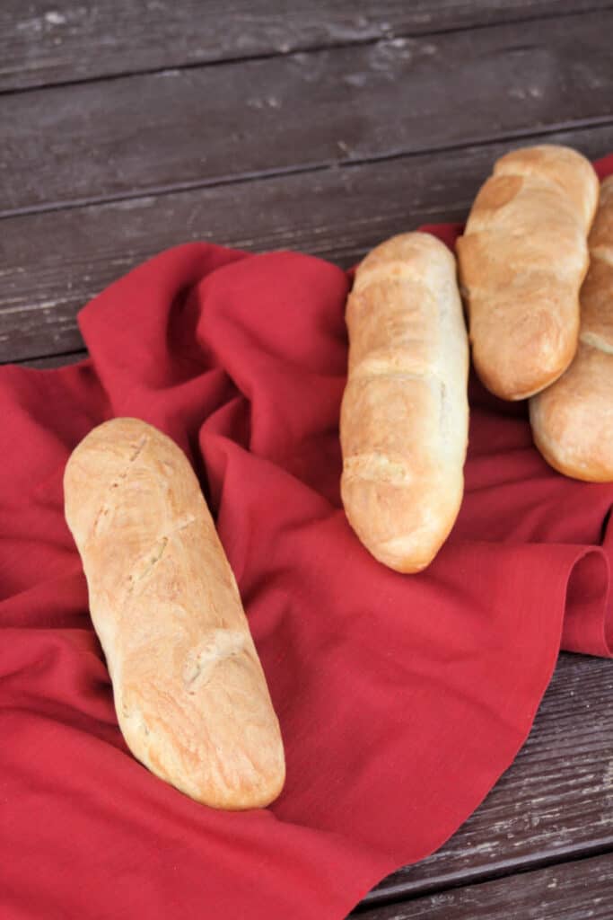Loaves of french bread on a red cloth.