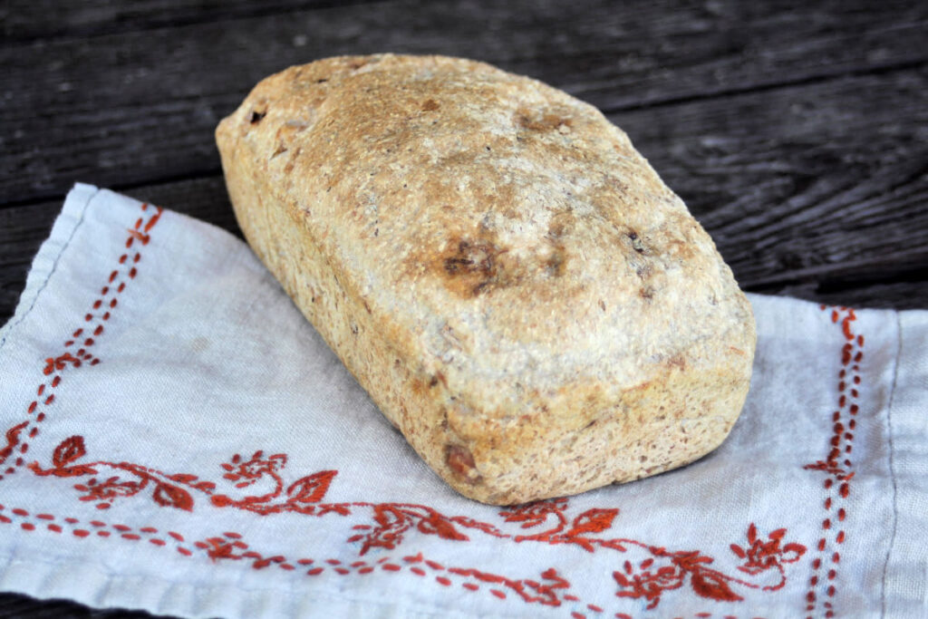 A loaf of ham bread sitting on an embroidered napkin.