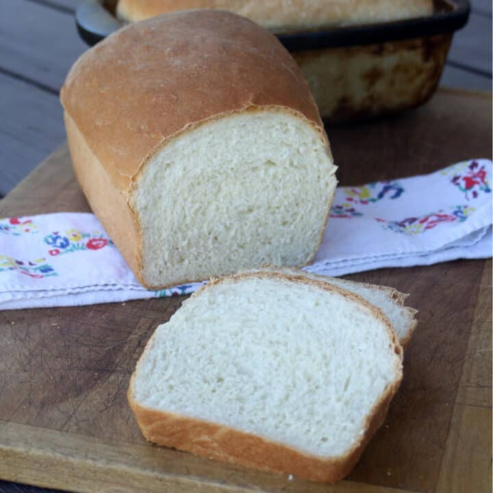 Slices of buttermilk bread sitting on a board with rest of loaf and floral napkin.