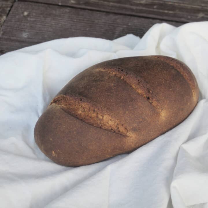 A loaf of pumpernickel bread on a white cloth.
