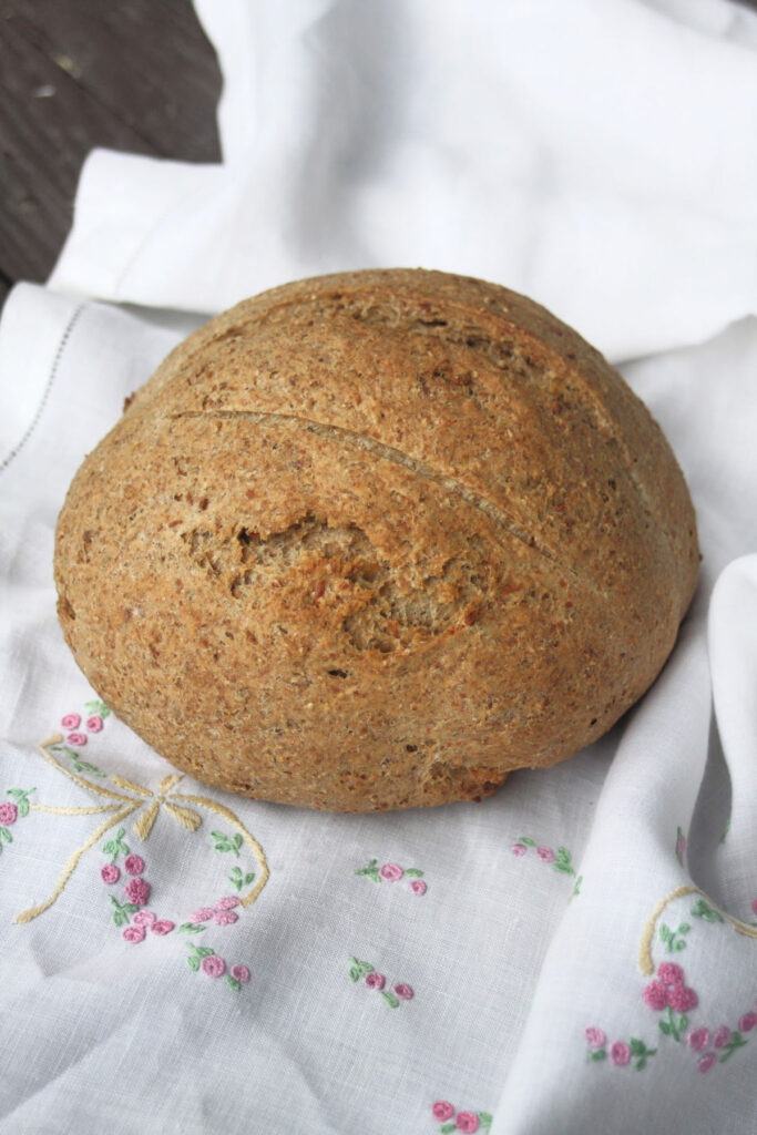 A round loaf of cheddar bread on a white linen napkin.