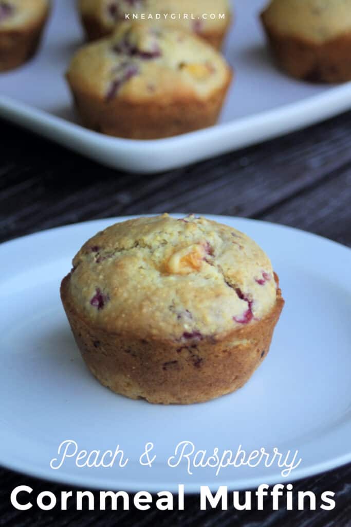 A peach and raspberry cornmeal muffin on a white plate with text overlay.