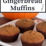 Pumpkin gingerbread muffins on a white plate with a pumpkin in the background and a text overlay.