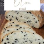 Slices of black olive bread on a board with remaining loaf in background wit text overlay stating olive bread.