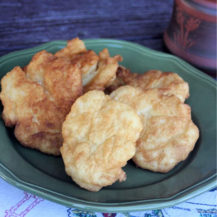 Pieces of fry bread stacked on a green platter.