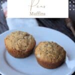 2 muffins on a white plate with a napkin, fresh pear, and honey dipper in the background with text overlay reading: pear muffins.
