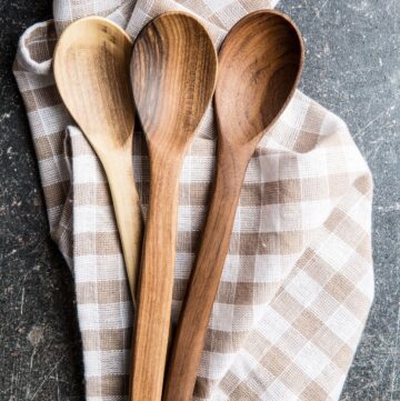 3 wooden spoons sitting on top of a brown and white plaid towel.