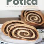 Slices of potica on a white plate sitting on top of a floral table runner with remaining loaf in the background with text overlay reading: Potica.
