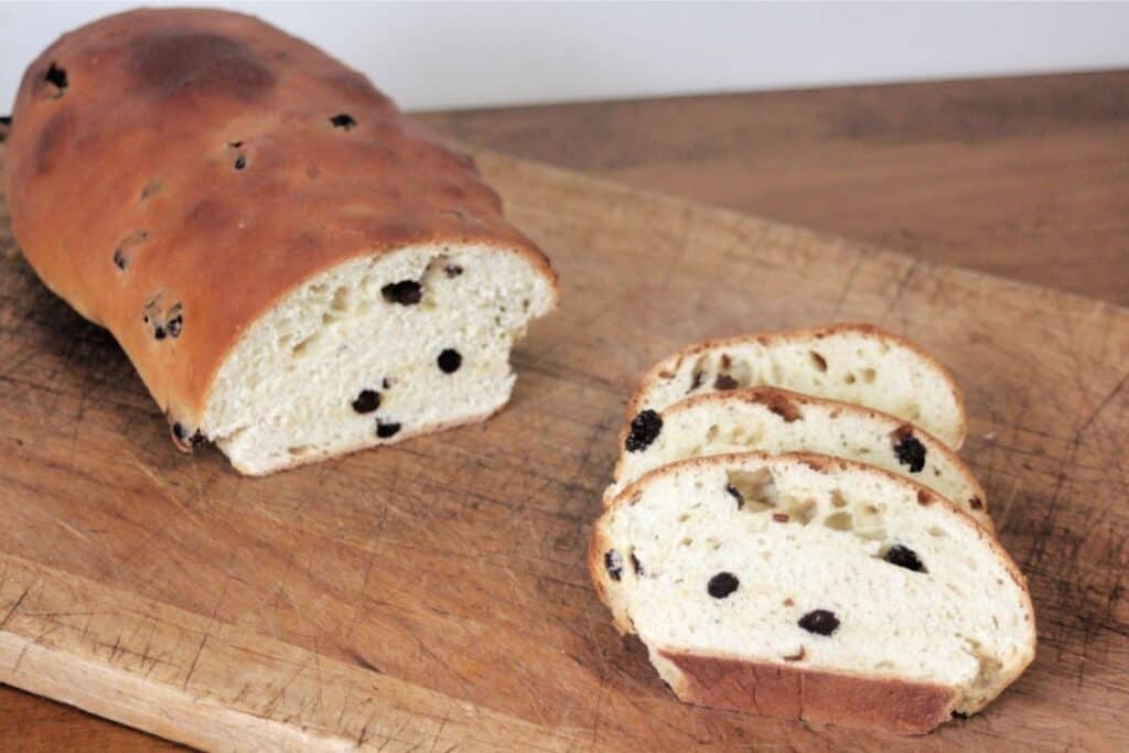 Slices of rum raisin bread sitting on a cutting board with rest of loaf sitting to the left.