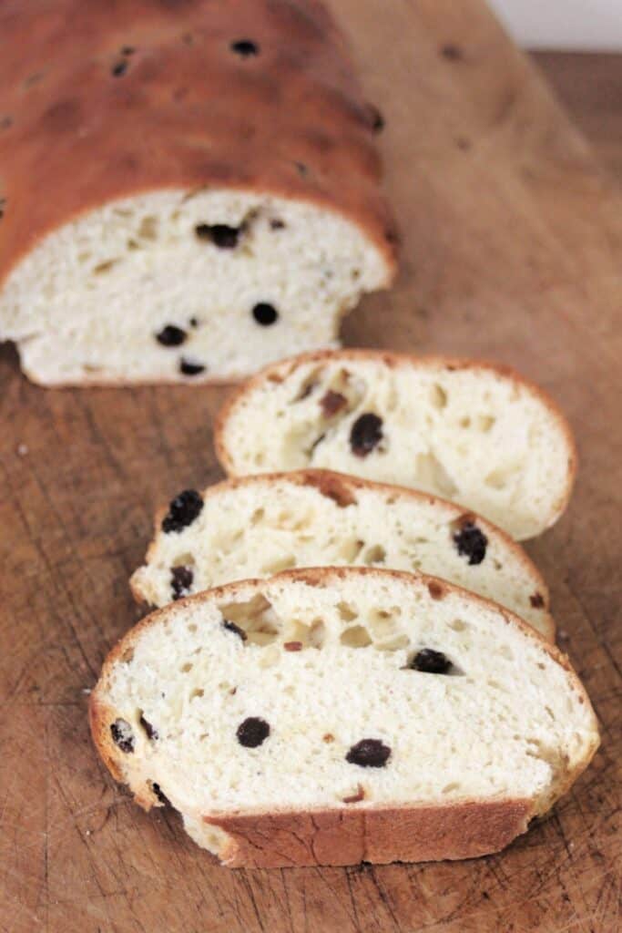 Slices of rum raisin bread sitting on a cutting board with rest of loaf sitting behind.