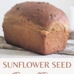A loaf of sunflower seed bread on a napkin sitting in front of a taper candle with text overlay reading sunflower seed bread recipe.