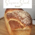 A loaf of bread with sesame seeds on the top sitting on a cutting board with text overlay stating: Sesame Seed Bread.