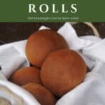Molasses brown bread rolls stacked in a white napkin lined basket with text overlay stating: dark dinner rolls.
