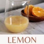 Lemon glaze in a clear glass pitcher in front of a wooden bowl with cut open lemons and text overlay stating lemon glaze.