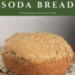 A round loaf of irish oatmeal soda bread sitting on a green and white table linen with text overlay stating Irish Oatmeal Soda Bread.