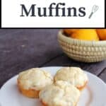 3 muffins on a plate with a basket of fresh meyer lemons in the background and text overlay reading: lemon muffins.