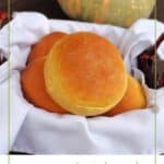 A white napkin lined basket full of pumpkin dinner rolls sitting in front of a green and orange striped pumpkin with text overlay stating: How to Make Pumpkin Rolls.