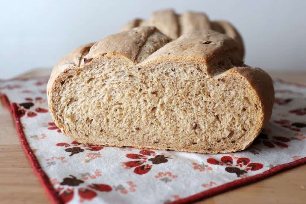 A round loaf of sauerkraut bread sitting on a napkin with the end cut off exposing seeds and texture inside.