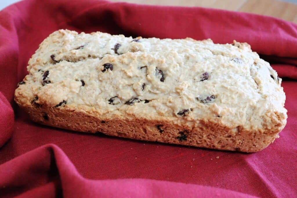 A loaf of coconut bread sitting on a red cloth. 