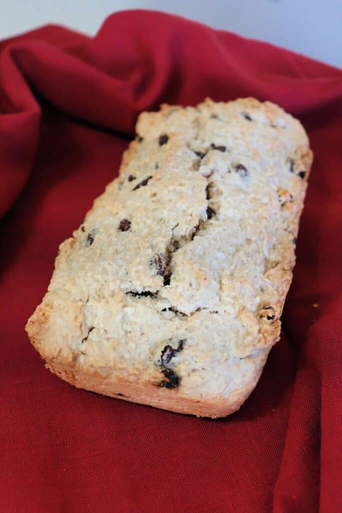 A whole loaf of Caribbean coconut bread sitting on a red cloth as seen from above.