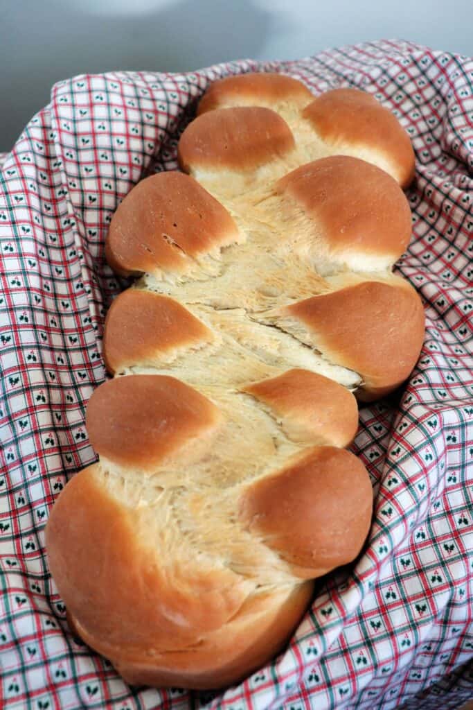 A braided loaf of bread sitting on a checked piece of cloth.
