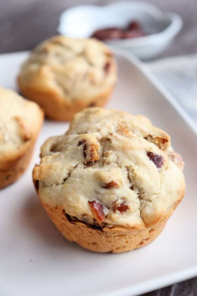 Close-up of a date walnut muffin on a white plate.