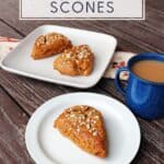 A white plate with a scone sitting on it, a blue cup full of tea next to it, a square plate with 2 scones on it in the background. Text overlay reads: homemade gingerbread scones.