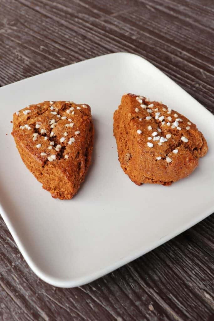 2 gingerbread scones sitting on a square white plate.