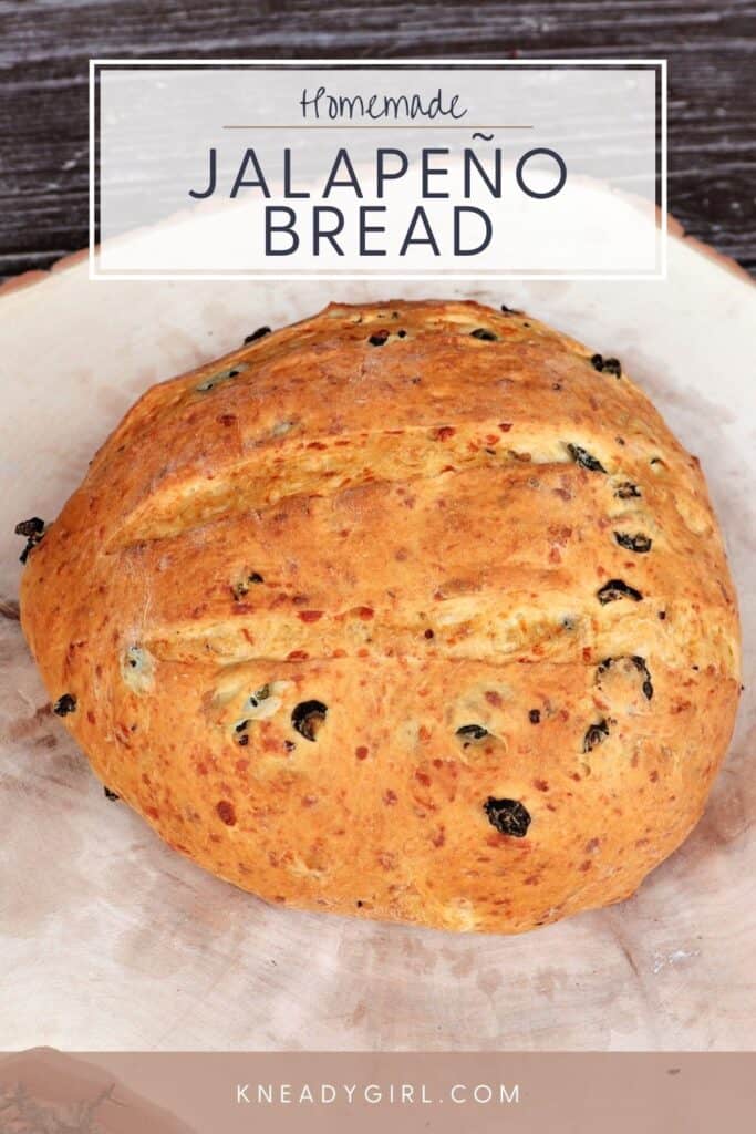 A loaf of bread studded with green peppers on a board with text overlay read: homemade jalapeno bread.