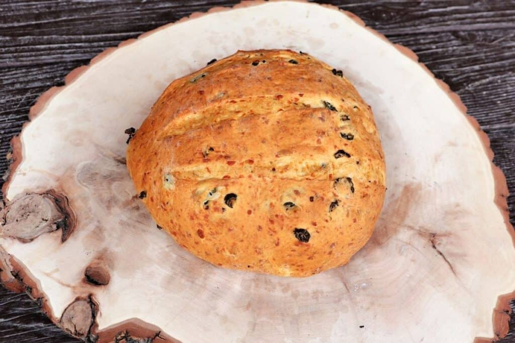 A loaf of cheddar jalapeno bread on a wooden board.