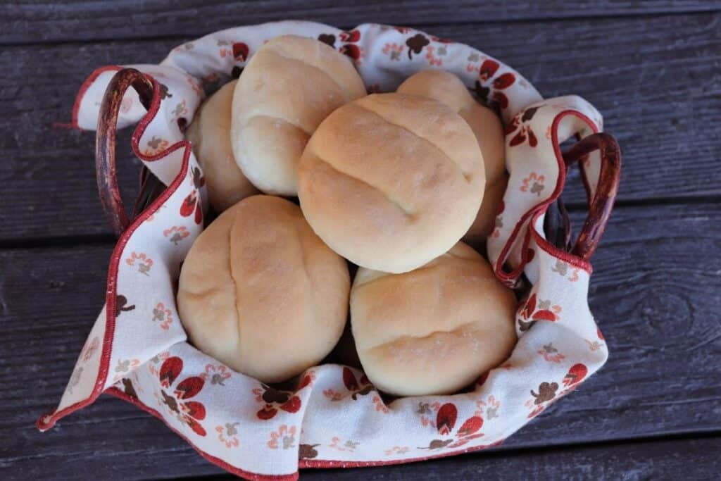 A linen-lined basket of stacked telera rolls as seen from above.