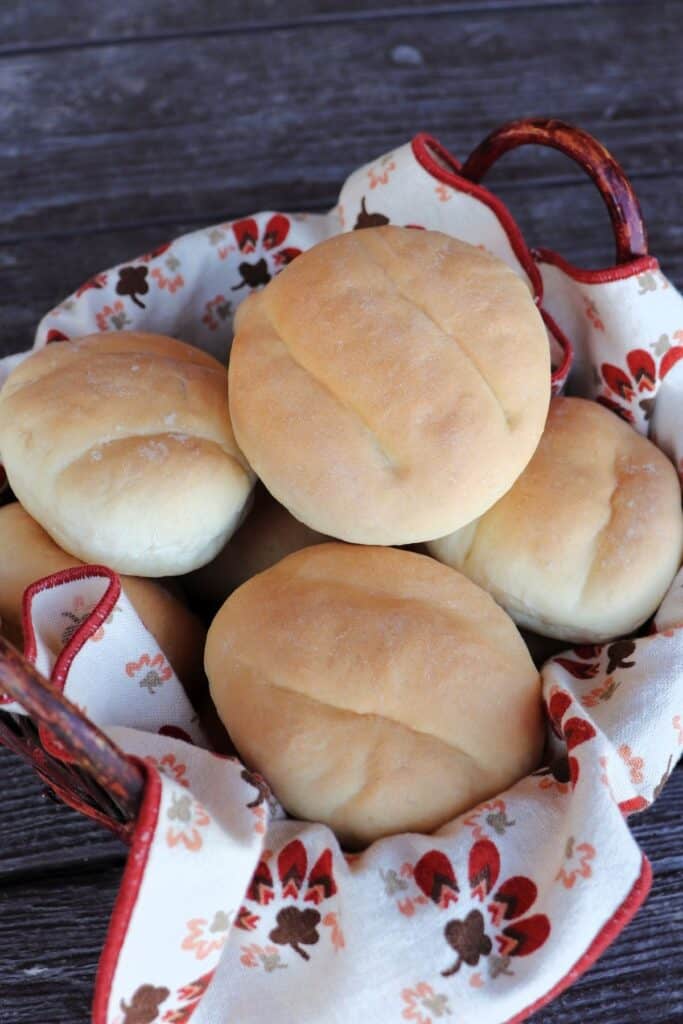 A linen-lined basket of stacked telera rolls as seen from above.