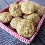 Applesauce bran muffins stacked in a basket lined with a red and white checkered cloth.