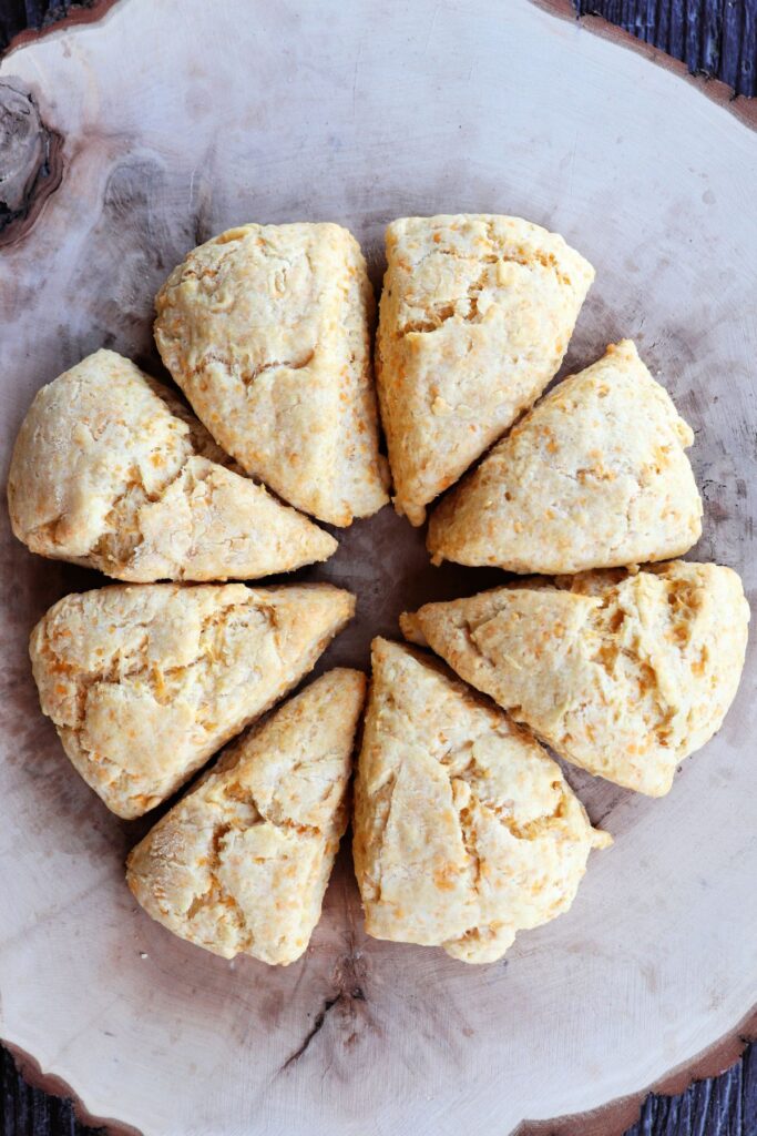 A ring of 8 triangle shaped scones sitting on a board as seen from above.
