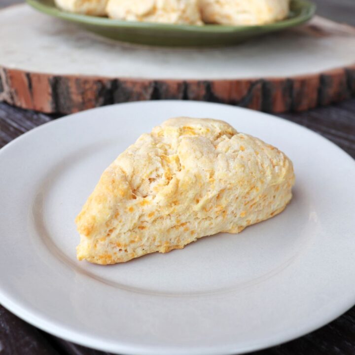 A cheese scone sitting on a white plate.