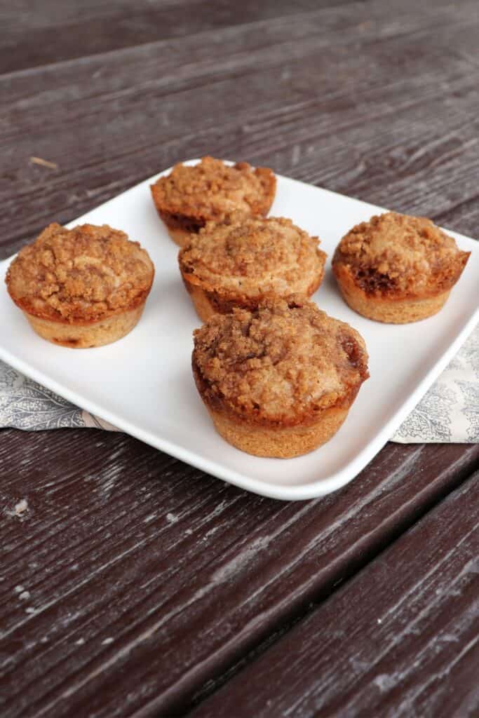 5 cinnamon muffins on a square white plate.