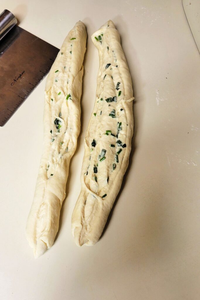 Raw bread sliced in half exposing layers of herb inside.