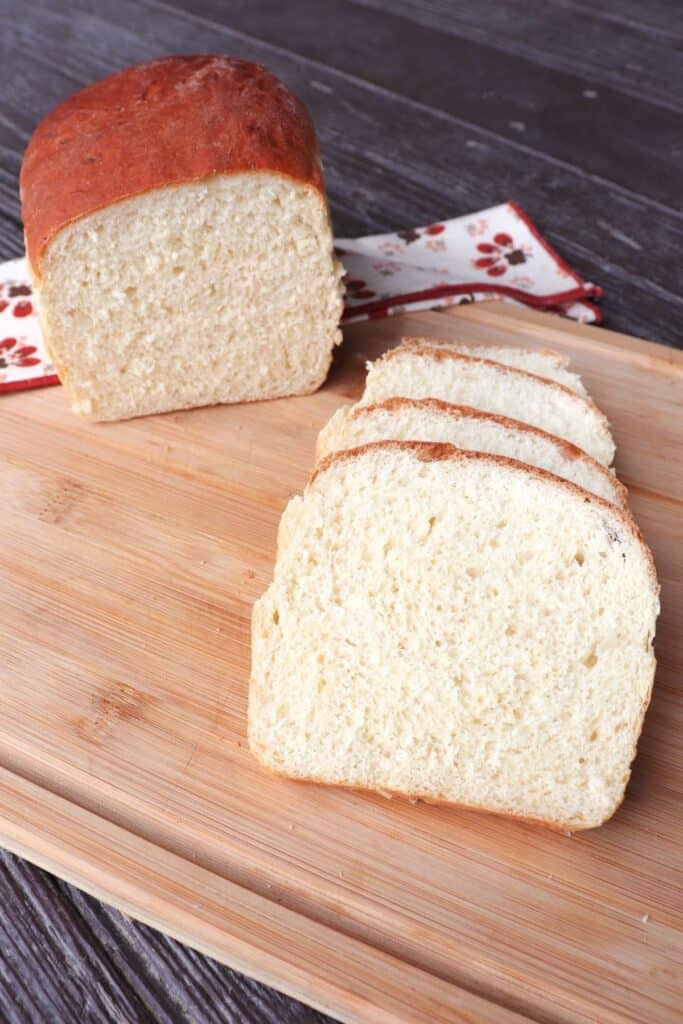 Slices of mashed potato bread on a board with remaining loaf sitting behind it.