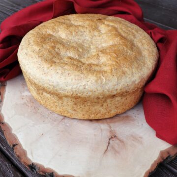 A loaf of shepherd's bread sitting on a board surrounded by a red cloth.