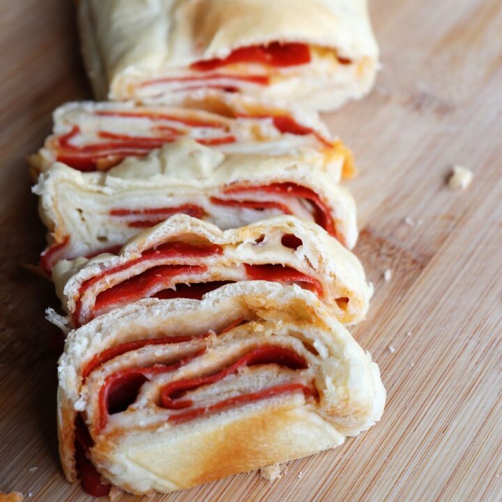 Slices of pepperoni bread stacked on a board, exposing the layers of bread, cheese, and pepperoni.