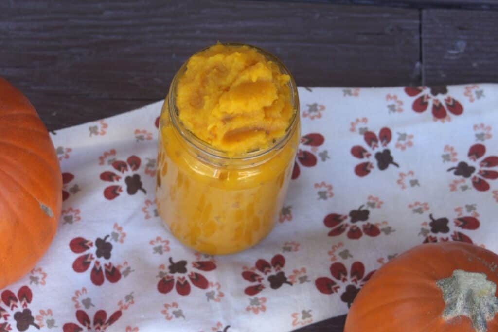 An open jar of mashed squash as seen from above sits on a cloth.